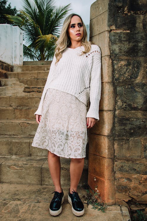 Free Woman in White Knitted Top Leaning of Wall Stock Photo