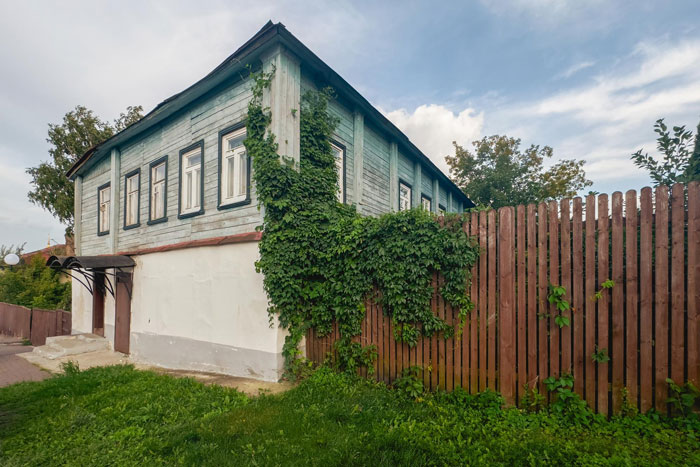 Old wooden house beside a wooden fence covered with greenery, illustrating a neighbor replacing a rotten fence dispute.